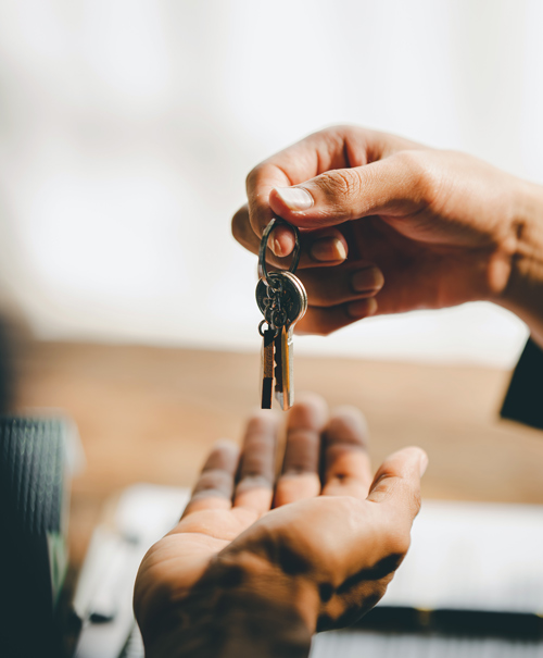 a person handing over keys to another person with three keys visible on the ring