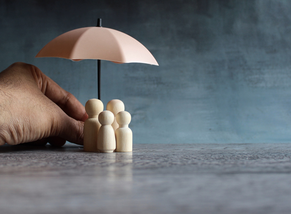 hand holding an umbrella over wooden figures representing safety and protection for a family or group in need of support and community 1 care