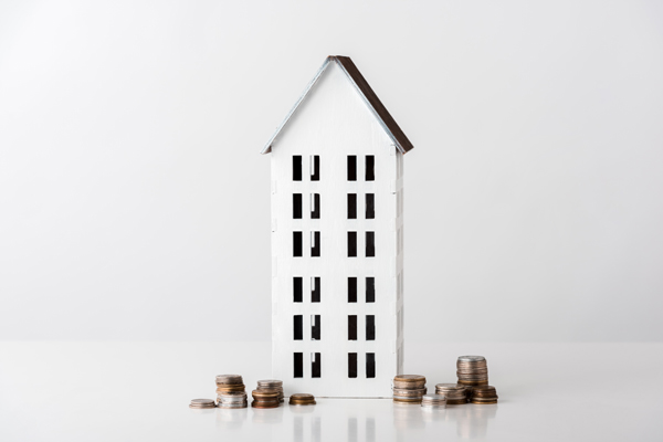 white model house with coins representing investment and financial savings